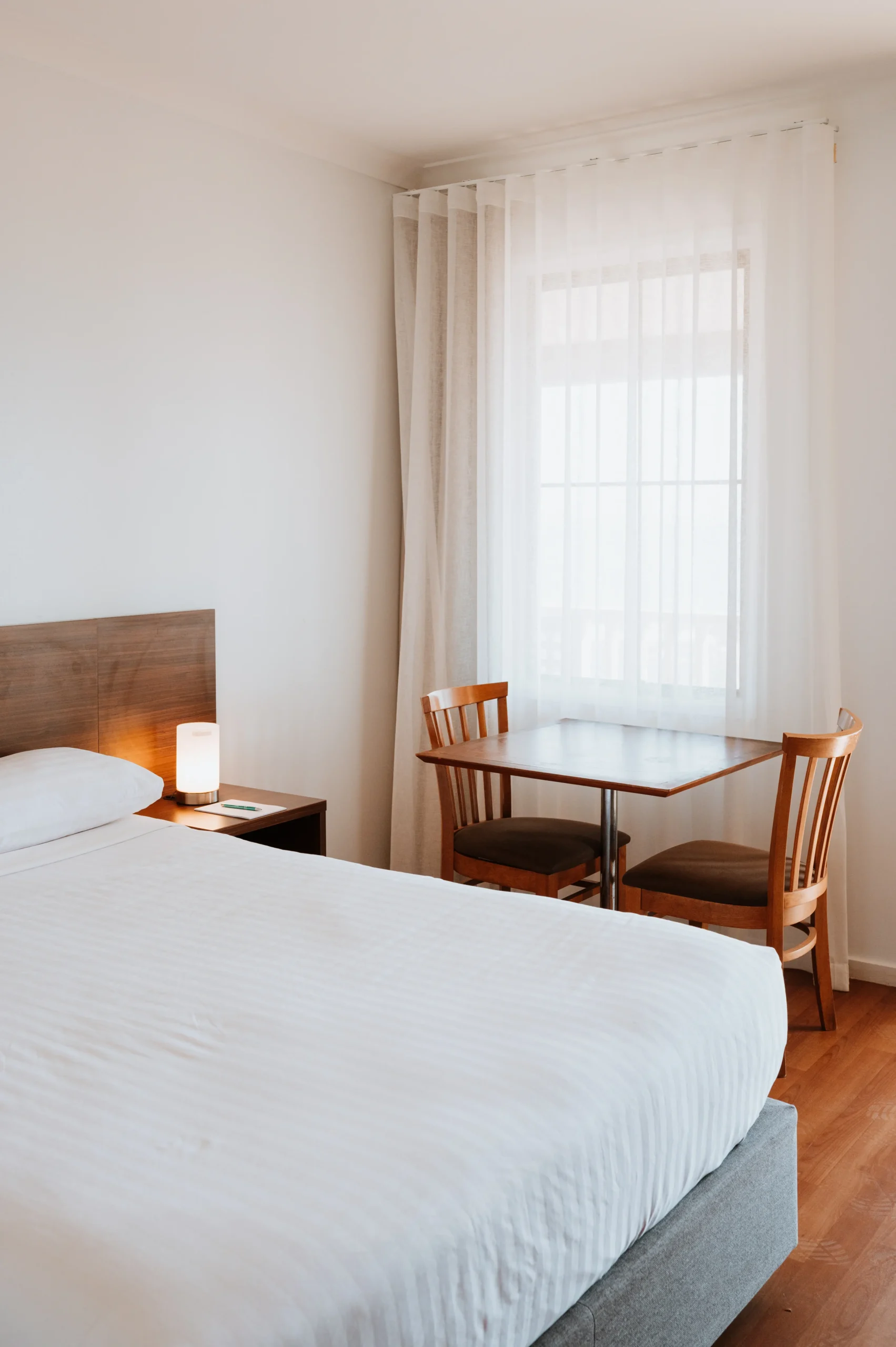 Photo of studio room with bed, two person dining set and a bright window