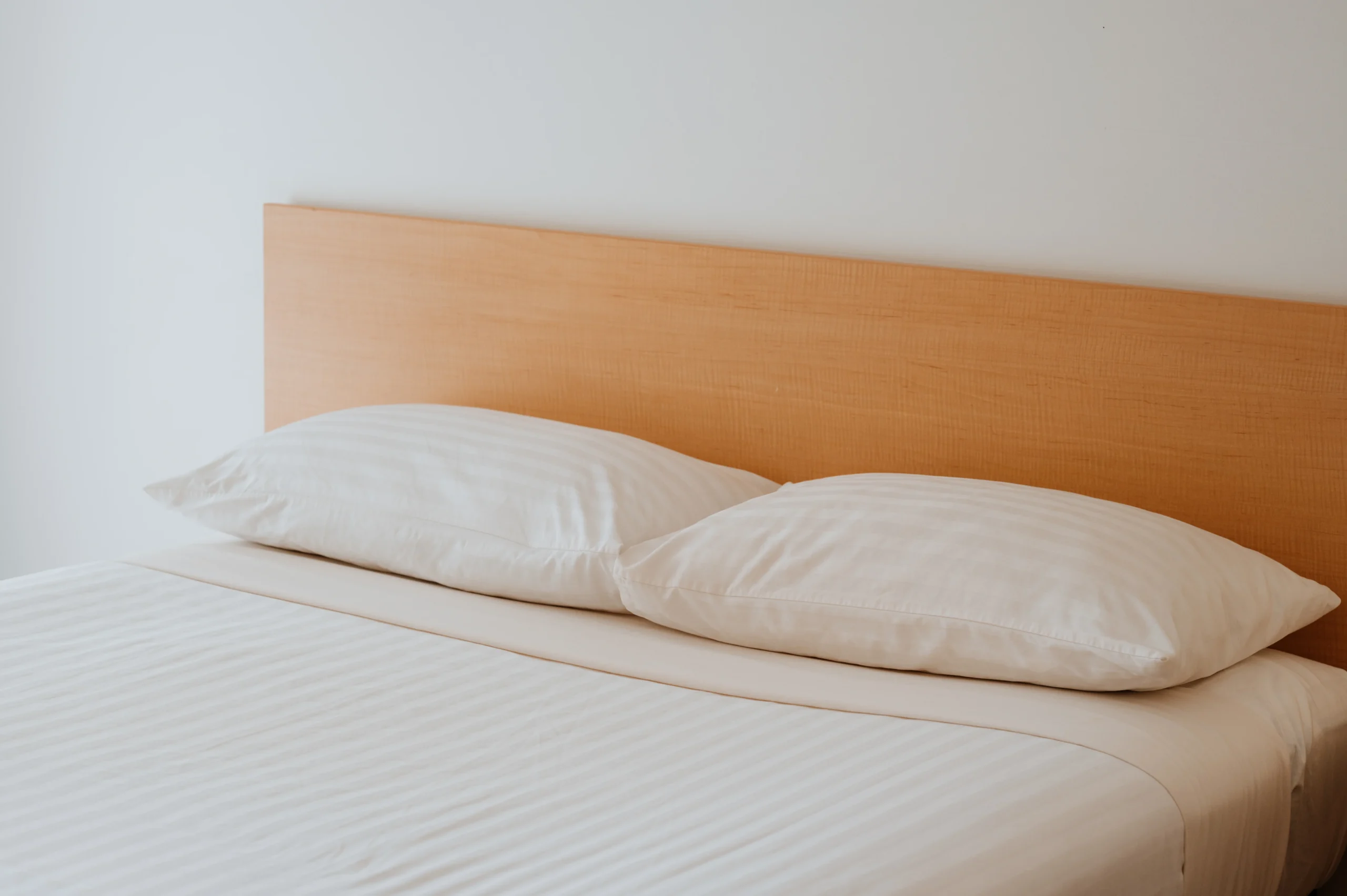 photo of headboard in bedroom at The Hedland Hotel. The white of the sheets matches the white in the walls