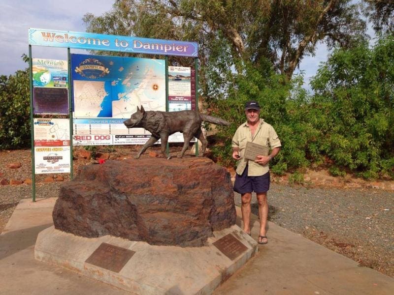 A man standing next to the Red Dog memorial statue in Dampier